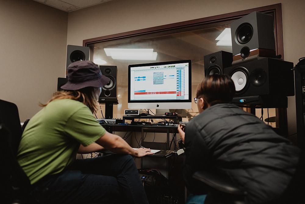 Two students work on an audio editing project together at a computer.